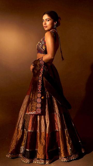 In a breathtaking black metallic lehenga by Aum, Bhumi Pednekar showcases a sleeveless blouse adorned with multicolor embroidery, shimmering sequins, and intricate beadwork. The flared silk skirt features harmonious hues and delicate embroidery at the waistline and hemline. Paired with an elegant tissue dupatta with embroidered borders, the ensemble is styled by Meagan Concessio. Accessories include a statement choker from Curio Cottage and matching earrings from Silver Streak.