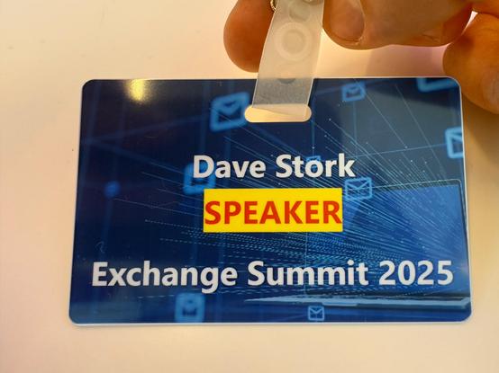 Close-up of a conference badge for the Exchange Summit 2025. The badge has a blue background with a digital network design featuring small envelope icons. The text reads "Dave Stork" in white, "SPEAKER" in bold red letters on a yellow background, and "Exchange Summit 2025" in white at the bottom.