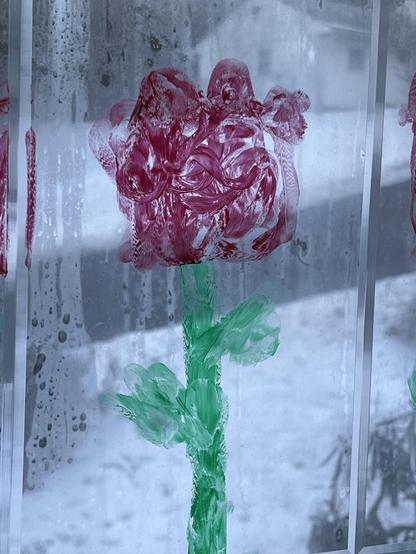 my 8yo granddaughter’s drawing of a red tulip. She used a washable marker on one of my windows, and to me it captures the essence of a showy ruffled tulip on a green stem. 