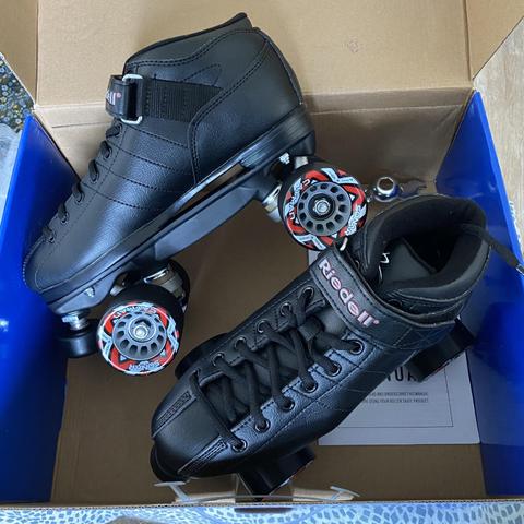 An open box with a pair of black speed quad roller skates (from the Riedell brand)