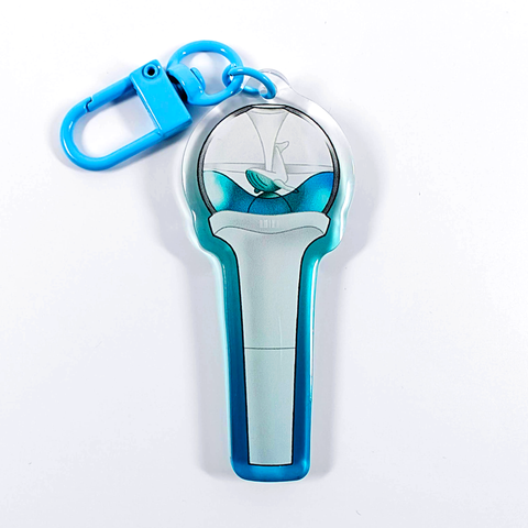 A picture of an acrylic keychain of a drawn version of NMIXX's newest lightstick. The rim of the keychain has an ombre that goes from blue at the bottom to clear at the top. It has a light blue clasp.