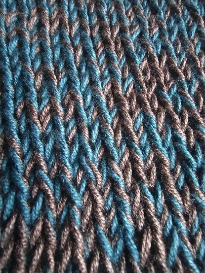 A close up of stockinette stitches made while holding two strands of yarn together, one blue and one grey creating a marbled effect.
