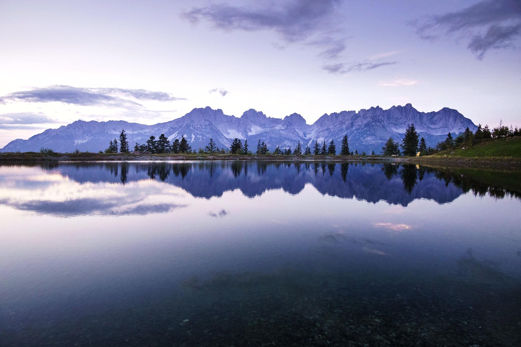 Eine Bergkette, der Wilde Kaiser, spiegelt sich in einem Bergsee. Ein Sommerabend, gegen Sonnenuntergang.