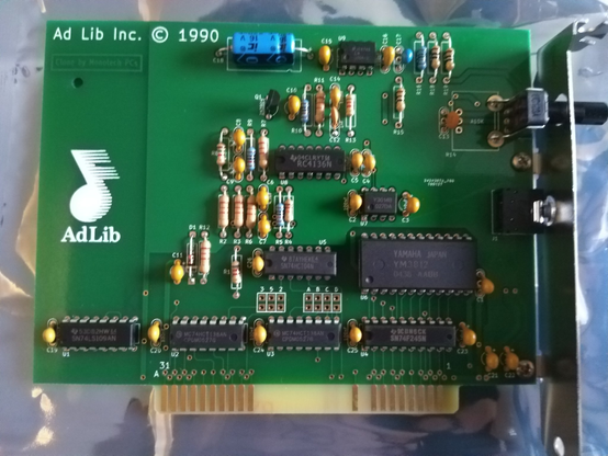 **TL;DR:** A replica AdLib sound card, a classic PC audio device from 1990, is displayed in protective packaging.  

This is a Monotech PCs clone of the AdLib sound card, originally released in 1990. The card features a green PCB with various resistors, capacitors, and IC chips, including the Yamaha YM3812 (OPL2) chip, which was key to FM synthesis sound in early PC gaming. The AdLib logo, with a stylized musical note, is prominently printed on the board. The gold edge connector is designed for ISA slots in vintage PCs. This card replicates the original AdLib experience for retro computing enthusiasts.