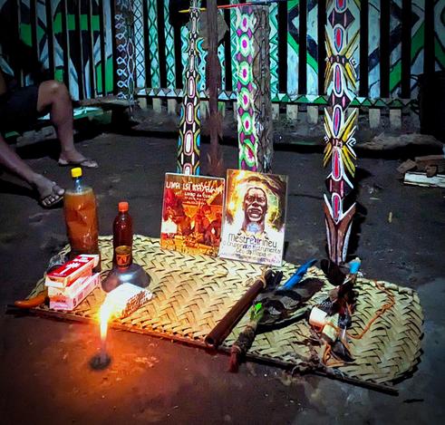 An altar with candles and sacred objects placed on the floor of a maloca.
