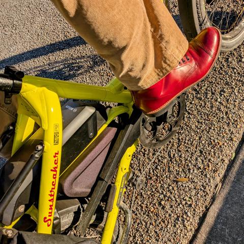A photo of my right foot on the pedal of a 

yellow Tern HSD cargo bike with its name, Sunstreaker, in red on the seat stay

I'm wearing

red captoe boots with under a tan corduroy pantleg

