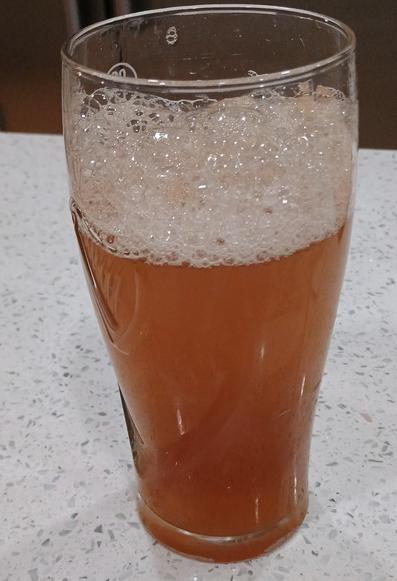 A beer glass contains a brown liquid with a foamy head. Looks rather like beer. 