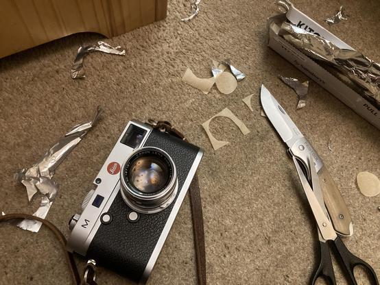 My Leica M240 and a Canon 50/1,8 sitting in a mess of scraps of tinfoil, greaseproof paper, my pocket knife and some scissors.