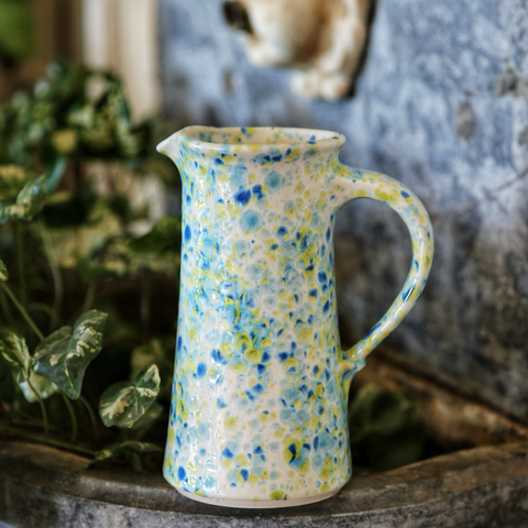 Un pichet de l’atelier de poterie Le Tour Des Rêves émaillée en blanc moucheté bleu clair bleu foncé et jaune citron 
