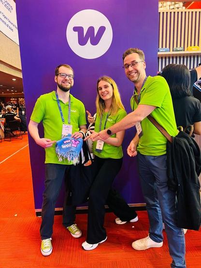 Niklas, Viola and Ronny from the Syde team while standing in front of a WooCommerce banner at WordCamp Asia 2025 in Manila. 