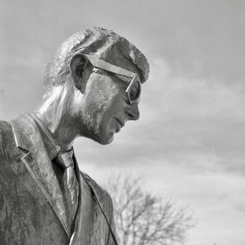 A black and white film photo. The bronze statue of rock ‘n’ roll legend Buddy Holly glows in the sun in Lubbock, Texas. Sunday, February 16, 2025.
