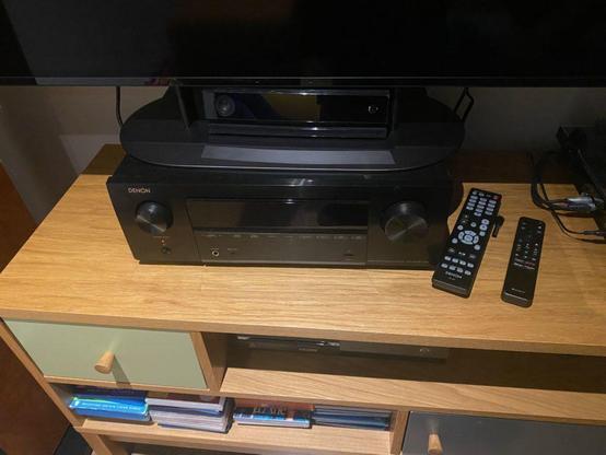 Black amplifier below a black TV, on a TV furniture