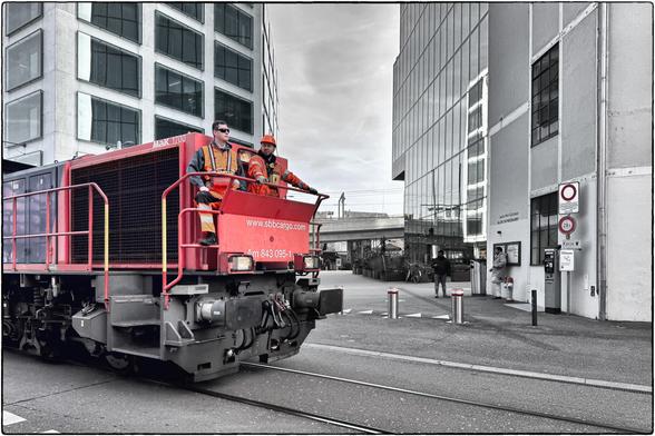 Schwarzweissfotografie mit Selektivfarbe rot einer fahrenden Rangierlokomotive in der Stadt Zürich