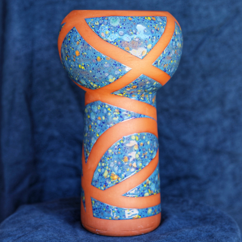 Vase en faïence rouge en forme de coupe avec un émaillage bleu clair moucheté de bleu foncé d’orange et de jaune, l’émaillage est ponctué de larges bandes laissant apparaître la couleur rouge orangée de la terre 