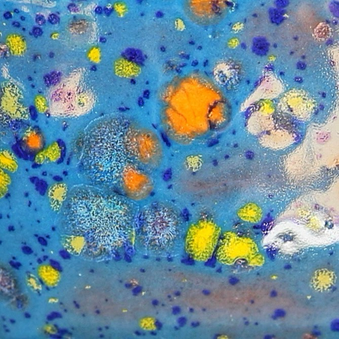 Close-up sur l’émaillage bleu clair moucheté de bleu foncé, de jaune et de orange 