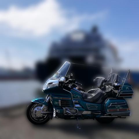 Motorrad Honda Goldwing, dahinter verschwommen ein Schiff auf der Mosel.