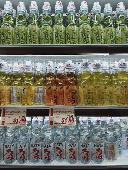 A supermarket shelf displaying colorful bottles of Hata Ramune beverages in various flavors including yuzu and orange.