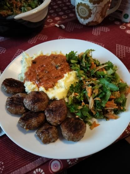 Mashed potatos, meatballs, salad and a sauce (made of tomato, onion, garlic and mushrooms) on the plate 