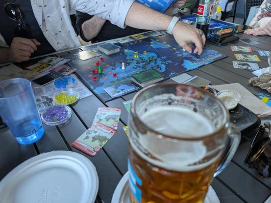 A table surrounded by friends with beers and the board game Pandemic
