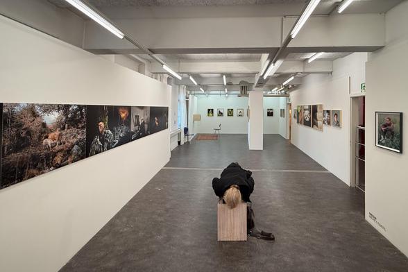 In der Fotoausstellung bäuchlings auf einer Bank liegen