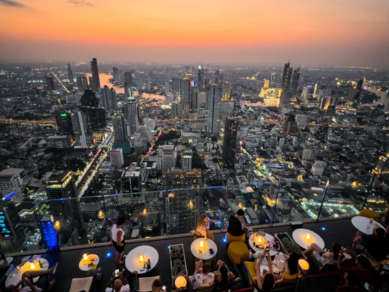 Die Skyline Bangkoks bei Sonnenuntergang. Der Himmel ist orange-rot.