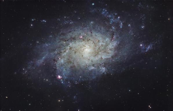 M33 — The Triangulum Galaxy. 

A large spiral galaxy with a soft white core, feathery blue spirals, and reddish blobs here & there that hint of nebula within the galaxy. 