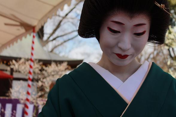 A geisha from the Kamishichiken hanamachi serves tea at Baika-sai.