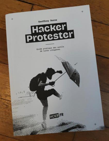 Photo du livre «Hacker protester» de Geoffrey Dorne. On y voit un·e manifestant·e qui frappe énergiquement du pied un objet, peut-être une bombe lacrymogène, pour le lancer au loin. Iel a un sac à dos et tient un parapluie ouvert dans la main droite, qui lui sert probablement de bouclier.