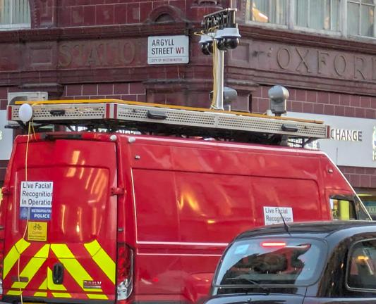 A red van with facial recognition cameras, and signs