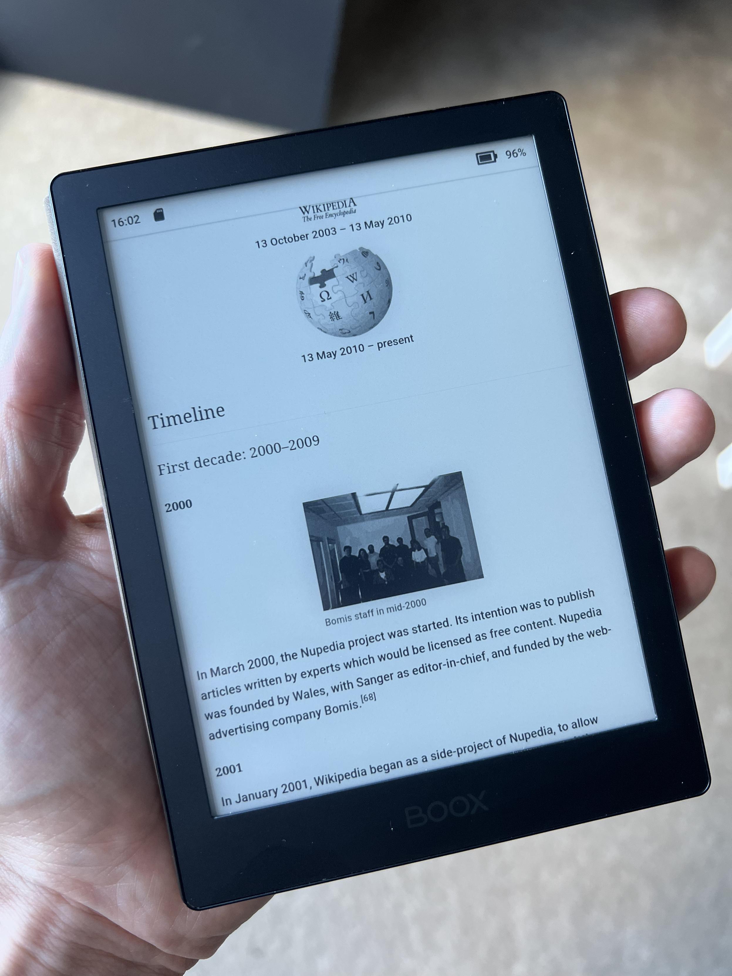 A  picture of a slim little e-reader (a Boox Poke) in some guy's hand, displaying the wikipedia page about wikipedia.