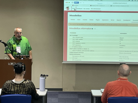 Presenter discussing MoodleBox with a slide showing MoodleBox information. 