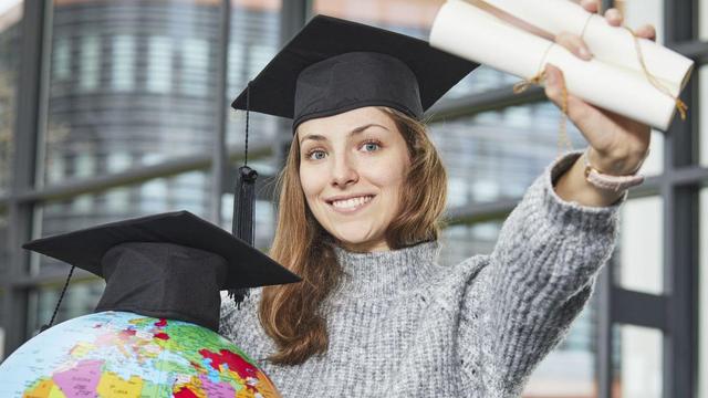 Symbolic picture: Student in mortarboard holding up a diploma