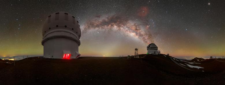 The Milky Way shares the stage with a luminous bubble of green and orange airglow in this panoramic image of Gemini North, one half of the International Gemini Observatory, supported in part by the U.S. National Science Foundation (NSF) and operated by NSF NOIRLab. Gemini North (right) is accompanied here by the Canada-France-Hawai‘i Telescope (CFHT) (left). In this image, you could remove all of the stars, the brilliant stripe of the Milky Way, and the nearby city lights of Hilo, Hawai‘i (far left), and you would still be left with a picture that isn’t completely dark. This is thanks to the persistent light of airglow.

Airglow is primarily caused by sunlight interacting with atoms and molecules in Earth’s upper atmosphere, which allows them to gain excess energy. This excess energy is then released as a particle of light called a photon. The frequencies of the photons determine the captivating colors of airglow. While it’s often difficult to see this light with the naked eye, a camera can capture it, as seen in the photo above. Intersecting the Milky Way is another lucent phenomenon known as zodiacal light with the gegenschein to the right.

This photo was taken as part of the NOIRLab 2022 Photo Expedition to all the NOIRLab sites. Petr Horálek, the photographer, is a NOIRLab Audiovisual Ambassador. Fulldome and extended view versions of this photo also are available.

Credit: International Gemini Observatory/NOIRLab/NSF/AURA/P. Horálek (Institute of Physics in Opava)