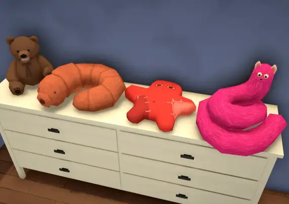 Another screenshot from the Patreon post, showing 4 plushies on a dresser : a brown teddy bear with a toothy smile, an orange earthworm, and red/orange star made of a patchwork of fabrics, and a long, long pink cat.