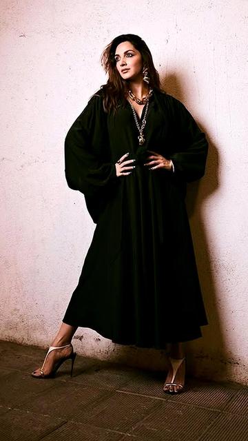 Kiara Advani made a striking appearance at the Tira Beauty store opening in Mumbai, donning a black Balenciaga dress with a deep V-neckline and billowy sleeves. The ensemble was accentuated with chunky gold jewelry, including layered necklaces and bangles. Her intense smokey eye makeup and loose, textured waves added to the edgy sophistication of the look. Styled by Anaita Shroff Adajania, Kiara's fashion-forward choice set new trends at the event.