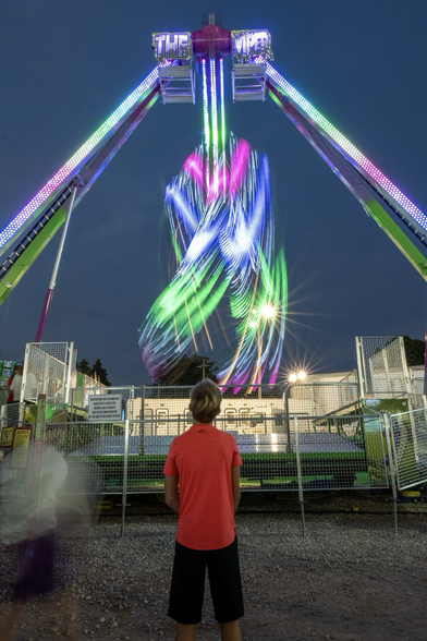 A young man watching a carnival ride in action