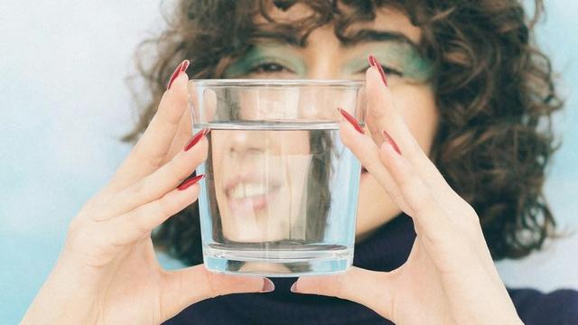 Person looking through a clear glass of water.