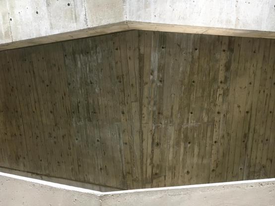 A textured concrete wall with several irregular holes, highlighting its aged and industrial appearance.