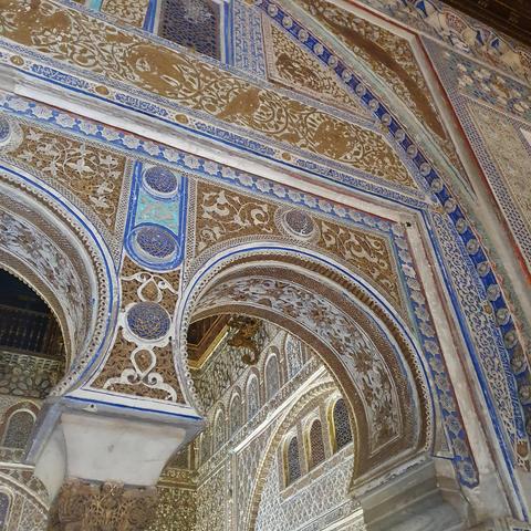 Elaborate archway with birds in gold and blue. Horseshoe arches that connect to Islamic architecture but the animals Show that it is not. 