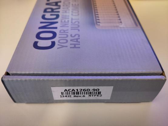 The usual Individual Computers box, which says "Congratulations, your new hardware just came home" with ACA1260-90 label on the side. Laying on a white table.