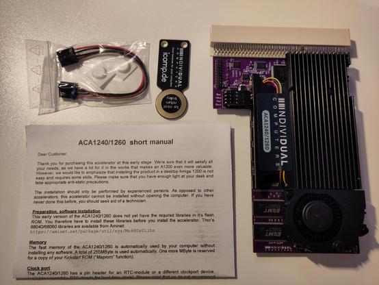 The contents of the box laid out, with short manual, some cables and feet, and a piece of merch, a token for a shopping cart, apparently, if I get it right.