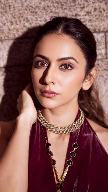 Rakul Preet Singh captivated fashion enthusiasts with her recent look—a burgundy metallic draped dress by Antithesis India. The gown's rich velvet fabric and elegant cowl effect highlighted her silhouette, while the daring halter design and thigh-high slit added a touch of boldness. Accessorized with a twisted gold choker and layered necklaces, Rakul's ensemble was a perfect blend of sophistication and allure.