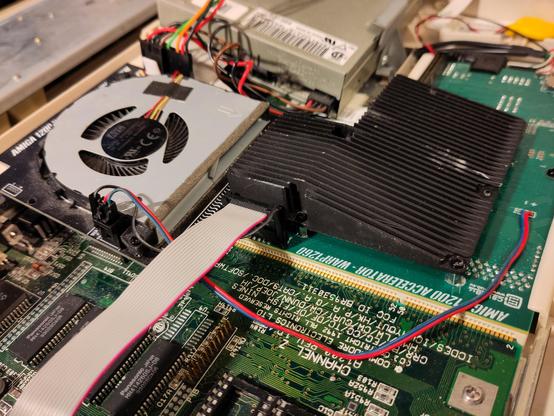 An opened Amiga 1200 with a side view at an installed Warp1260 and its cooler. installed. The radial fan cooling solution is next to the floppy drive, near the wide part of the trapdoor slot, towards the back of the machine. It blows air onto a black wedge-shaped large heatsink mounted on the '060.