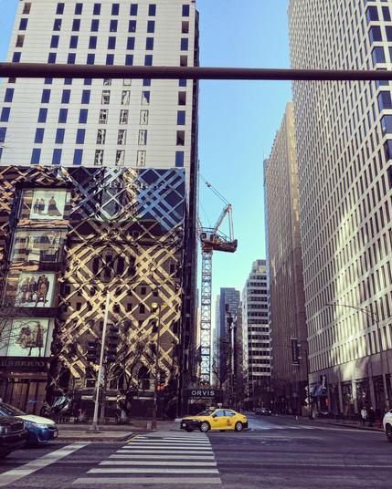 Facade of the Burberry flagship store on Michigan Avenue. A crane is stationed in the street on its south side, and a yellow taxi is driving past it (turning north into Michigan Avenue).
