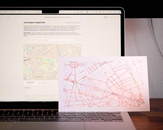 A post card with multi-colored lines in front of a computer screen showing a website with a map matching those lines.
