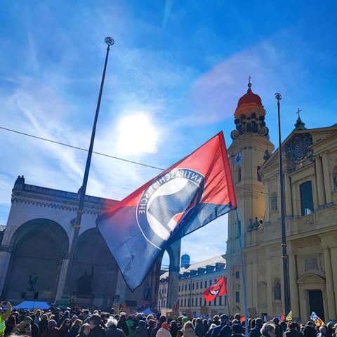 Foto von der heutigen Demo gegen rechts auf dem Odeonsplatz in München.
AntifaFlaggen im Gegenlicht über der Menschenmenge im Hintergrund die Feldherrnhalle und die Theatinerkirche.
Über allem der weiß-blaue bayrische Himmel.