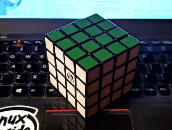 Ułożona kostka rubika 4x4 leży na klawiaturze laptopa