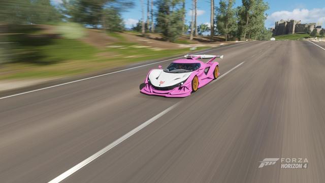 An Apolo IE in Forza Horizon 4, with Bamburgh Castle in the background. The car is sporting a pink and white livery based on the colour scheme of the Gen 1 Transformer Arcee. Where the Autobot logo would normally be, is the stylized logo of the band Cybertronic Spree.