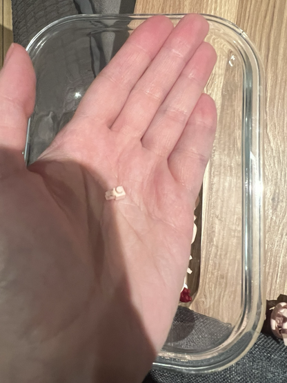 Photo of my hand holding one of the tiniest pale pink pieces of this flego set, a hinge that attaches one of the flower petals.