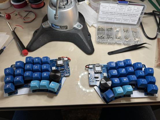 Klein split keyboard halves on a table with various tools used to build it.